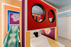 Experience a vibrant space where playful colors and themed decor spark your imagination. The bold red walls and whimsical designs enhance the sleek green slide, creating an inviting atmosphere for both relaxation and fun.