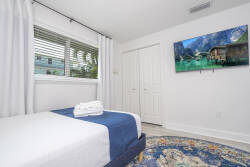 This bright bedroom, with its crisp white walls and soft natural light, creates a peaceful atmosphere. The textured area rug adds warmth, while blue accents on the bedding bring a refreshing touch. Enjoy a serene escape.