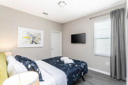 Enjoy a cozy bedroom with soft gray walls and stylish decor that promotes relaxation. The plush bed, adorned with a patterned throw, invites you to unwind, while natural light fills the room through the elegantly dressed window.