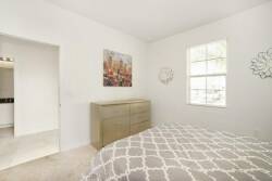 This bright and airy bedroom, featuring soft neutral tones, offers a calming atmosphere. A stylish geometric comforter covers a plush bed, enhanced by tasteful wall art and elegant decor for a sophisticated feel.