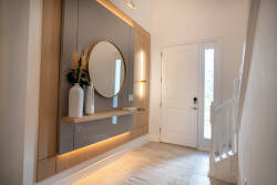 Welcome to a welcoming entryway filled with natural light, featuring a stylish door, a chic round mirror, and sleek wood accents. The muted tones and elegant decor create a warm atmosphere to greet you from the start.
