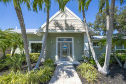 Welcome to this charming vacation home, nestled among lush palm trees and vibrant landscaping. The sleek glass door at the entry invites natural light in, creating a relaxing atmosphere for your enjoyable stay.