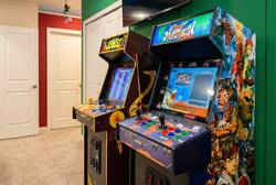 Enjoy a fun game room corner with arcade machines, colorful controls, a wall-mounted TV, bright green walls, and playful decor, creating a great space for family entertainment during vacation.