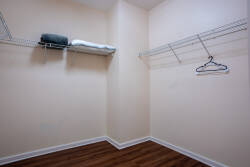 Enjoy the convenience of a spacious closet with sleek shelving and a warm wood floor that enhances the soft wall color, keeping your belongings organized and easily accessible throughout your stay.