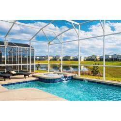 Relax in a screened outdoor pool area with a private pool, spa, lounge chair, sunny patio, and peaceful lake views, perfect for enjoying the Florida weather.