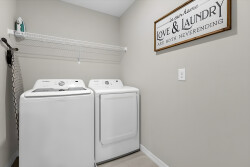 This laundry room is designed for your convenience, featuring spacious white machines that make doing laundry a breeze. A charming sign adds warmth, inviting you to enjoy the simplicity of daily chores during your stay.