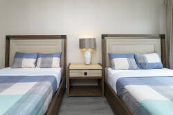 Bright and airy, this cozy bedroom features two twin beds with soft, inviting linens in calming blue tones. The sleek wooden headboards and modern lamp add a touch of warmth, perfect for restful nights after your adventures.