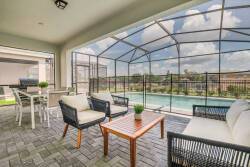 Discover a serene retreat on this screened-in patio, complete with comfy wicker seating and a stylish wooden coffee table. Take in the beautiful view of the shimmering pool, perfect for relaxation and leisurely mornings.