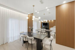 This stylish dining area boasts a sleek black table and soft upholstered chairs, enhanced by warm wood paneling and bright fixtures.