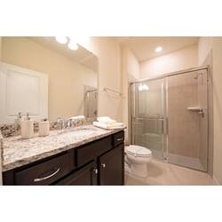 Refresh in a bright bathroom with a granite vanity, large mirror, glass shower, neutral tile, soft lighting, fresh towels, and clean details for vacation comfort.