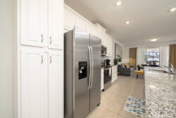 This stylish kitchen boasts sleek stainless steel appliances and bright white cabinets, creating an airy feel. Elegant granite countertops and colorful tile accents inspire culinary creativity and invite social gatherings.