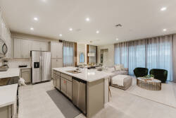 This bright, open kitchen and living area boasts sleek stainless steel appliances and light cabinetry, ideal for culinary adventures, while soft seating and large windows create a welcoming space to relax and unwind.