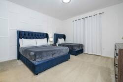 Experience a cozy haven with two plush velvet beds in rich blue tones, ensuring restful nights. Soft neutral walls and gentle lighting create a calming atmosphere, while elegant textures invite you to unwind in style.