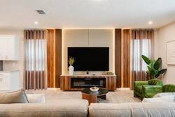 Welcome to a stylish living area with vibrant green armchairs that brighten the soft neutral décor. A sleek wooden media console holds a large TV, while warm lighting creates an inviting atmosphere for your stay.
