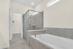 Experience a beautifully designed bathroom with sleek gray tile and a spacious glass-enclosed shower. Unwind in the elegant soaking tub as natural light pours in, creating a serene and inviting atmosphere for your relaxation.
