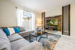 Relax in the cozy living room filled with natural light, featuring a soft gray sectional, a colorful area rug, and a chic wooden accent wall. This inviting space is ideal for unwinding and chatting after your adventures.