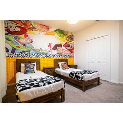 Rest in a colorful Toy Story themed bedroom with two cozy beds, playful character mural, wood furniture, and fun cow-print blankets. Bright colors, soft carpet, and cheerful details create a fun space for kids during vacation.