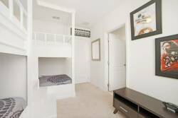 Bright and cheerful, this cozy children's room features a stylish bunk bed with soft bedding, offering a fun sleeping arrangement. The playful artwork and neutral tones create a welcoming atmosphere for relaxation and play.