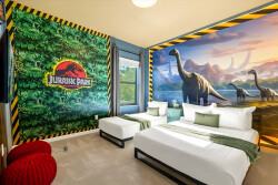 Step into a world of adventure in this vibrant guest room, featuring playful Jurassic Park murals that ignite the imagination. The cozy twin beds, adorned with soft green throws, invite relaxation after a day of exploration.