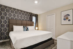 This cozy bedroom features a stylish upholstered headboard and a chic patterned wall, creating a sophisticated backdrop. Soft lighting enhances the plush textures, while minimal decor promotes a calming atmosphere for restful.