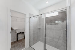 Step into a bright, contemporary bathroom featuring sleek glass shower doors and stylish gray tile that adds a touch of sophistication. The thoughtful layout maximizes space, making it easy to unwind and refresh.