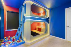This vibrant sleeping nook features a cozy bunk bed surrounded by bright blue and red walls, complemented by whimsical lighting that brings a sense of fun and sparks imagination, making it a perfect retreat for your stay.