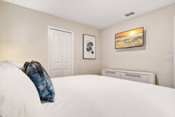 Enjoy peaceful nights in this beautifully designed bedroom with a cozy white bed and a vibrant blue accent pillow. Soft lighting enhances the serene artwork, while the modern dresser offers convenient storage for your belongings.