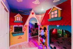 Enter a whimsical playroom with bright, colorful walls and charming cottage decor. Delight in the cheerful windows and playful Mickey Mouse figure, creating a magical atmosphere for children to explore and enjoy.