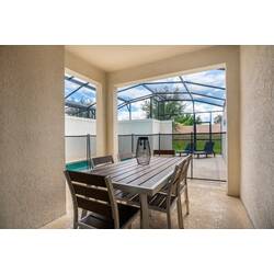 Step into a bright, screened-in patio that seamlessly connects indoor and outdoor living. The sleek metal dining set invites you to enjoy meals with a view of the greenery beyond, creating a refreshing atmosphere for relaxation.