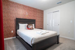 Relax in a cozy bedroom with a charming brick accent wall that adds character. Enjoy plush bedding and decorative pillows in soothing neutral tones, plus ample closet space for a clutter-free and welcoming stay.