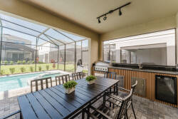 Enjoy our spacious outdoor dining area featuring a sleek black table, ideal for al fresco meals under soft lighting. The grill and refreshing pool view set the stage for inviting and relaxing gatherings.