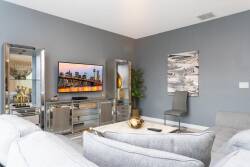 This bright and stylish living room boasts a plush white sectional and sleek metallic accents, creating a contemporary vibe. With modern decor framing the large TV, it's the ideal spot to relax after a day of adventure.