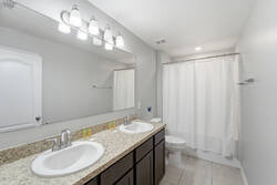 Refresh in a bright bathroom with a double vanity, granite countertop, large mirror, soft lighting, shower-tub combo, and clean finishes, creating a practical space for your vacation.
