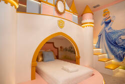 Step into a whimsical bedroom that sparks imagination, featuring a cozy bed nestled beneath a castle-like arch. The playful pink and gold accents create a cheerful atmosphere, complemented by a charming mural of a princess nearby.