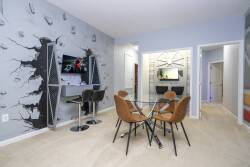 This stylish dining area features a sleek glass table surrounded by warm, tan chairs, perfect for enjoying meals or planning your day. The unique wall art adds character, while the cozy carpet enhances the inviting atmosphere.