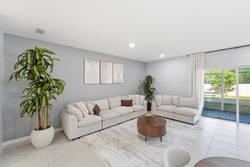 Gather in a bright open living and dining area with a cozy sectional sofa, wood dining table, modern lighting, greenery, and a nearby kitchen, creating a comfortable space for your vacation.