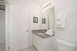 Step into a bright and clean bathroom featuring a sleek granite countertop and fresh white towels, enhancing the crisp, airy vibe. The subtle artwork adds a touch of personality, making this space as functional as it is welcoming.