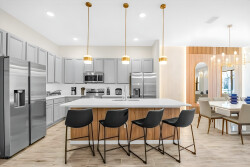 Experience a stylish kitchen featuring sleek stainless steel appliances and warm wood accents. The spacious island with chic black bar stools invites casual dining, while soft lighting creates a modern yet inviting atmosphere.