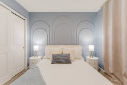 Unwind in this beautifully designed bedroom featuring a calming blue accent wall that enhances the cozy vibe. Enjoy restful nights on plush bedding alongside sleek nightstands and modern lamps for a tranquil retreat.