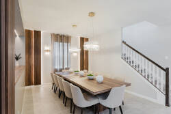 Enjoy the natural light in this stylish dining area, complete with a striking wooden table and plush white chairs. Elegant gold fixtures and warm wood accents make it the perfect setting for shared meals and conversations.