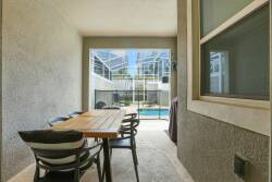 Step outside to your private outdoor dining area, where a sleek wooden table invites you to enjoy meals al fresco. Surrounded by a screen enclosure, this space offers a seamless view of the sparkling pool, perfect for relaxation.
