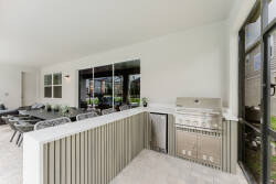 Step outside to a chic al fresco dining area with stylish rattan seating and a built-in grill, ideal for evening barbecues. Large windows flood the space with natural light, seamlessly connecting you to the lush greenery outside.