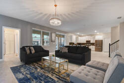 Experience a stylish living area with plush dark sofas perfect for relaxation, a chic glass coffee table, and a vibrant rug. Large windows fill the space with natural light, creating a warm and inviting atmosphere for your stay.