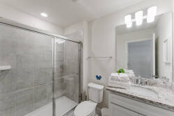 This bright, stylish bathroom boasts elegant gray tiles and a spacious glass shower for a refreshing start. The granite countertop adds sophistication, and plush towels create a cozy touch for your comfort.
