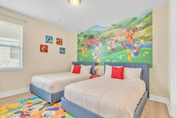 Sleep in a cheerful Mickey themed bedroom with two cozy beds, colorful wall art, soft bedding, red accents, bright natural light, and playful decor, creating a fun space for families.