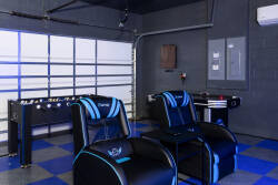 Step into a game lover's haven with sleek black and blue recliners that invite relaxation, complemented by a foosball table and a stylish garage backdrop. This space promises hours of entertainment and a unique touch to your stay.