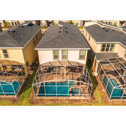 Enjoy an aerial view of the home’s screened outdoor area with a private pool, relaxing spa, covered patio, lounge space, and a bright setting for sunny Florida days.