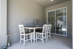 This bright dining area features a sleek white table and sturdy chairs, perfect for meals or games. Large sliding doors bring in natural light and connect you with beautiful views, creating a welcoming, contemporary atmosphere.