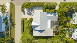 This aerial view highlights a lovely home nestled in lush greenery, offering privacy and tranquility. The light-colored roof beautifully matches the vibrant landscaping, creating a bright and cheerful atmosphere for your stay.