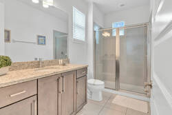Freshen up in a bright modern bathroom with a granite vanity, large mirror, glass shower, soft towels, natural light, and clean neutral finishes for a comfortable stay.